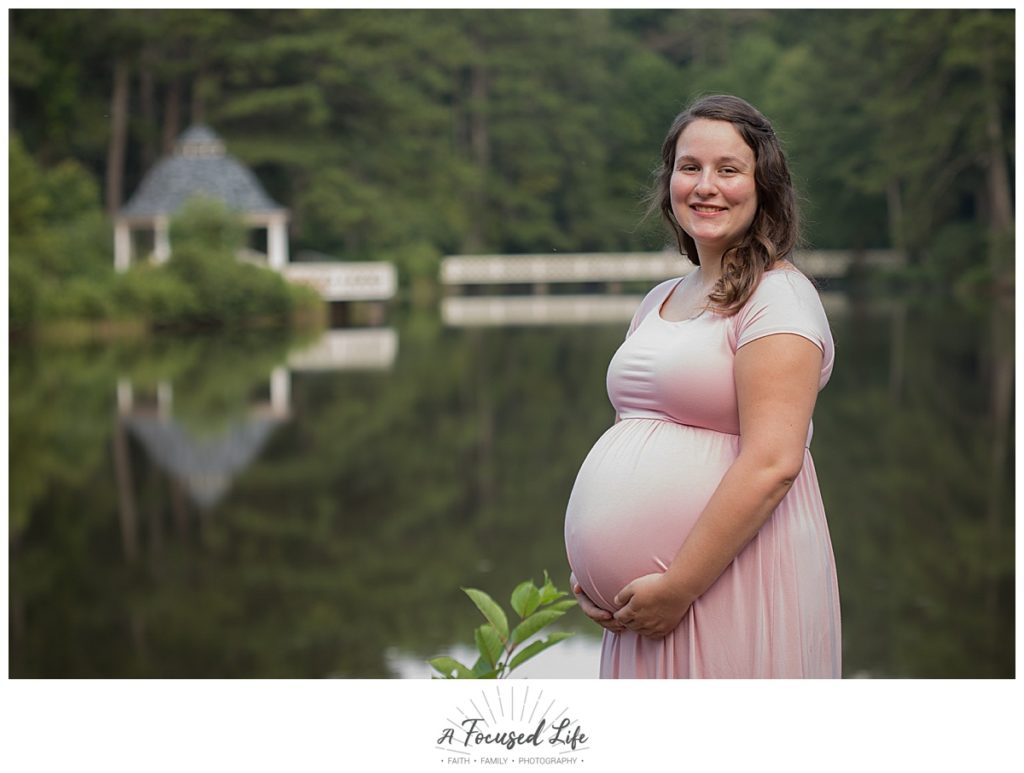Pregnant mom posing for maternity pictures at lake at Vines Park in Loganville