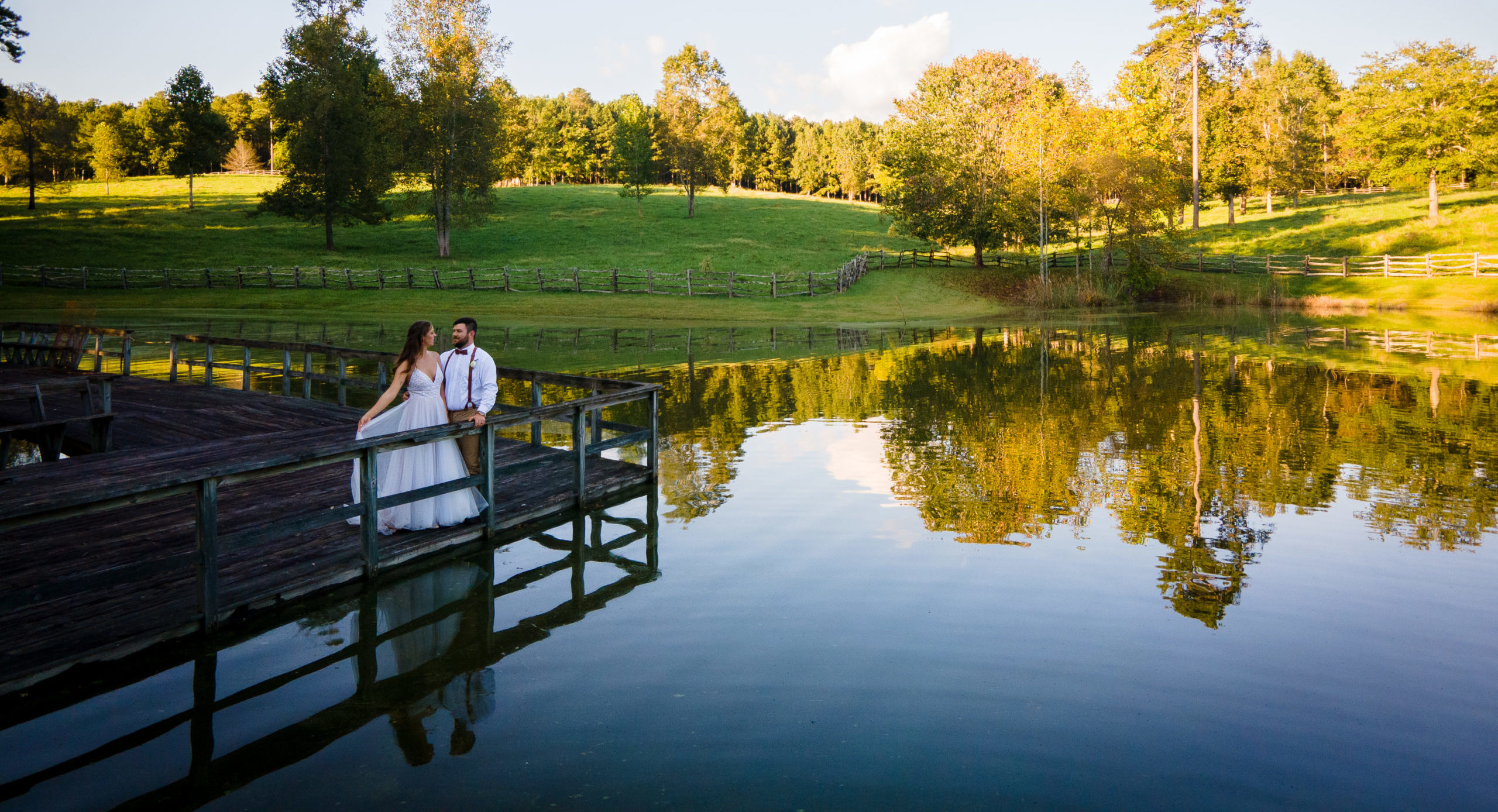 Bride and groom on dock in front of lake at The Walters Barn