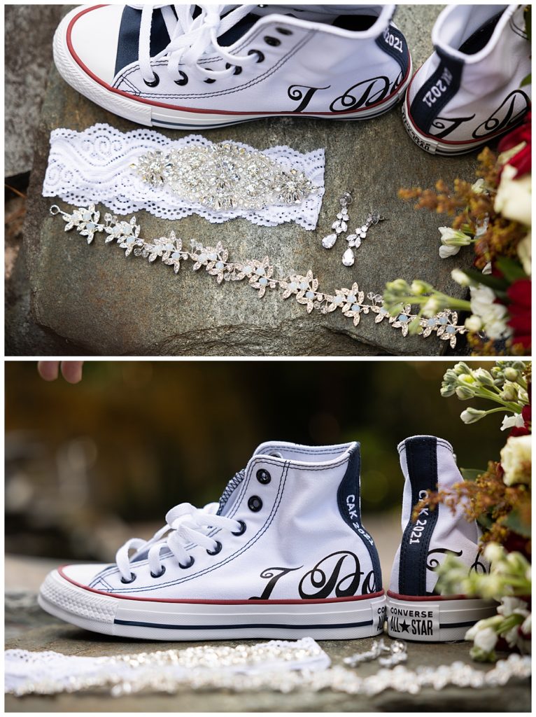 Close up shot of bride’s personalized Converse Chuck Taylor shoes and jewelry against a natural landscape