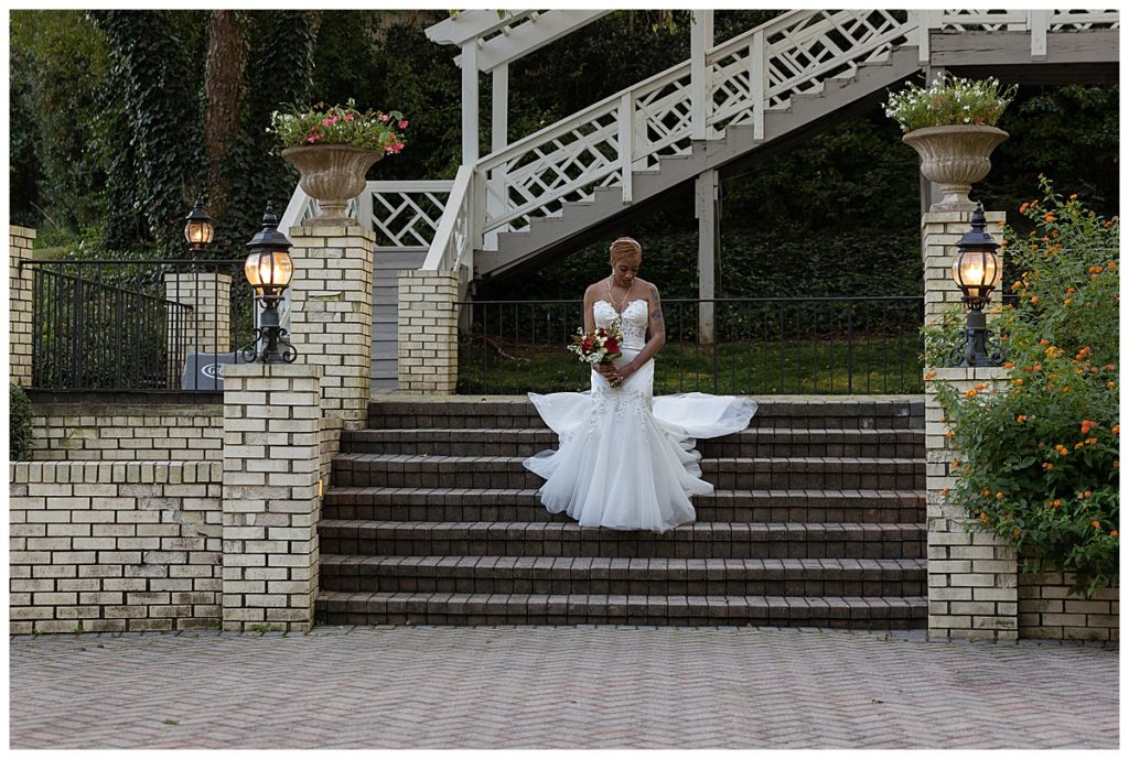 Bride outside on long steps with dress hanging behind her at Vines Mansion in Loganville GA
