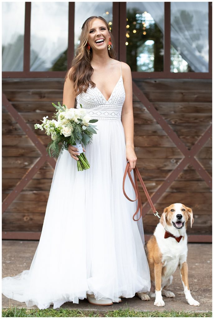 The bride in her dress with her dog outside on wedding day