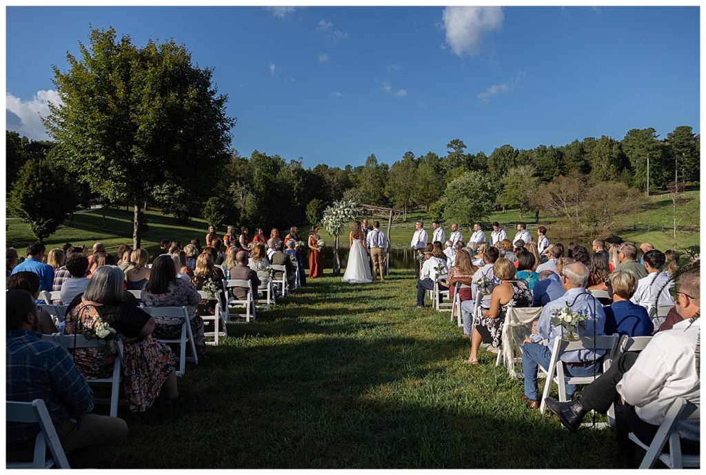 Picture of outdoor ceremony with green grass and trees and blue sky in the background