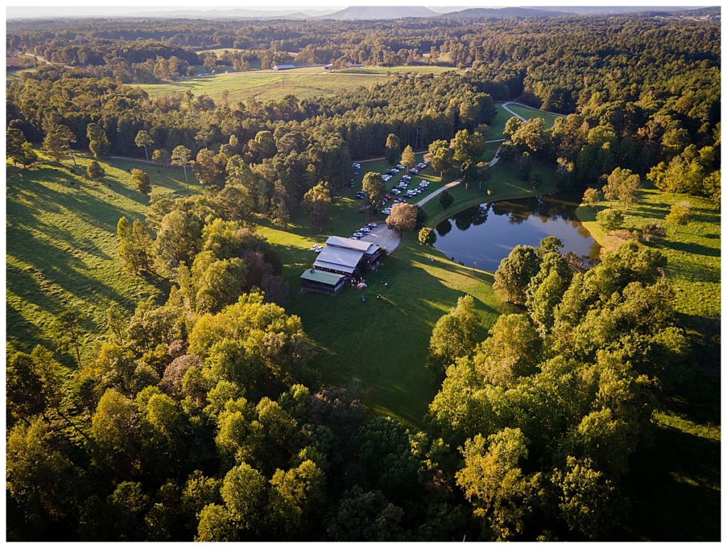 Aerial shot of the venue showing barn and water surrounded by trees Walters Barn in Lula GA