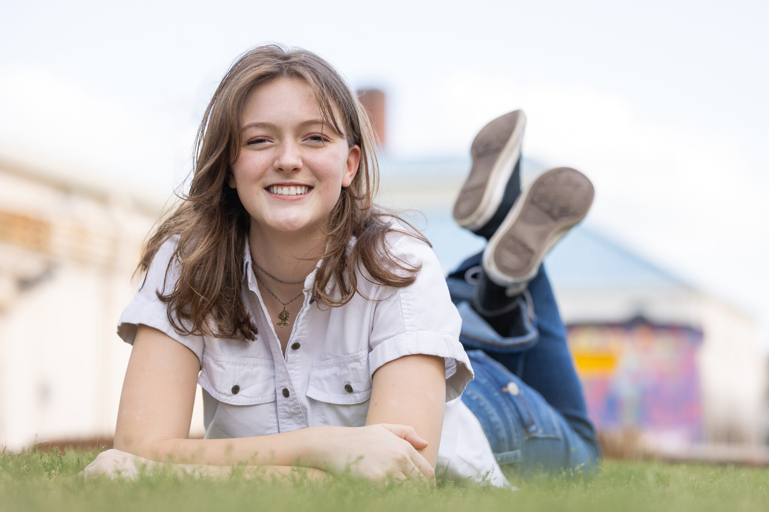 A young woman smiles while lying on the grass, captured by a photographer in Monroe, GA.
